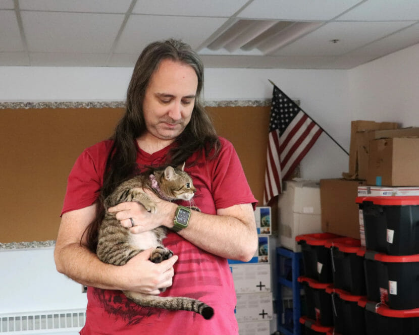 A person in a red shirt holds a cat