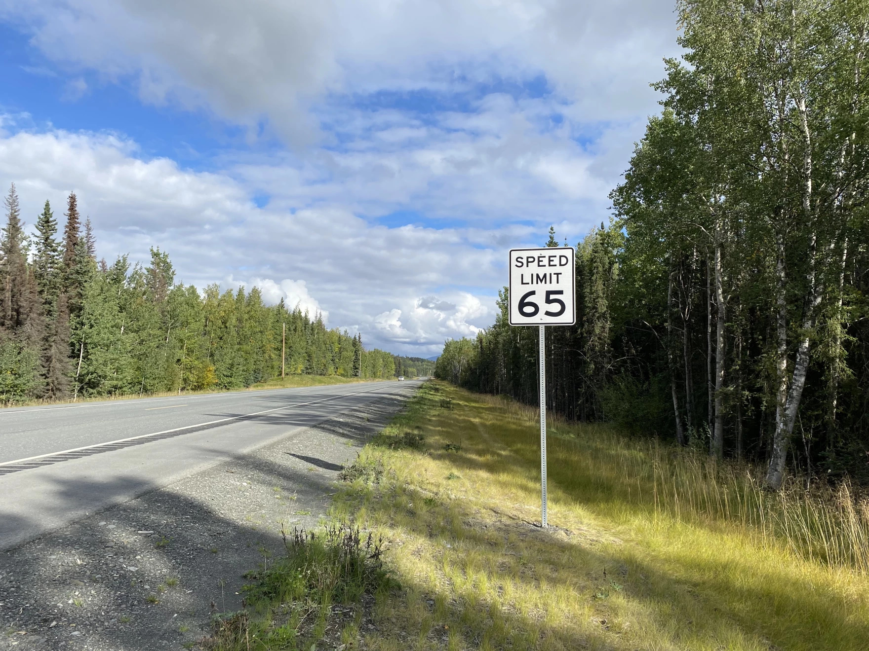 a speed limit 65 mph sign on a stretch of road