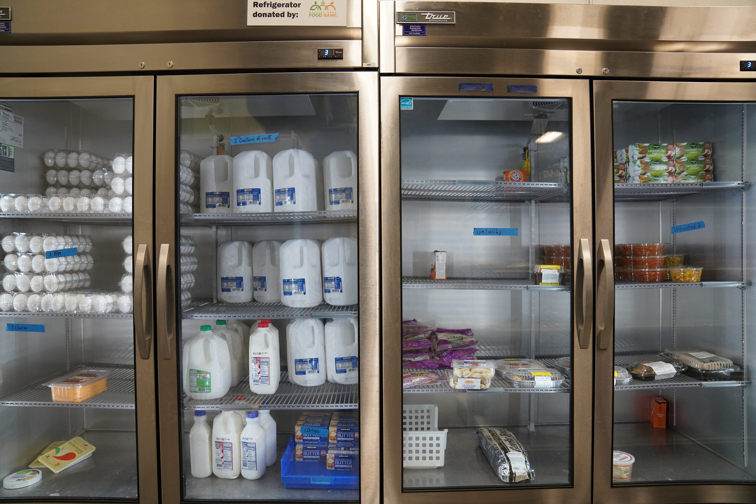 large industrial refrigerators filled with milk, eggs and other food