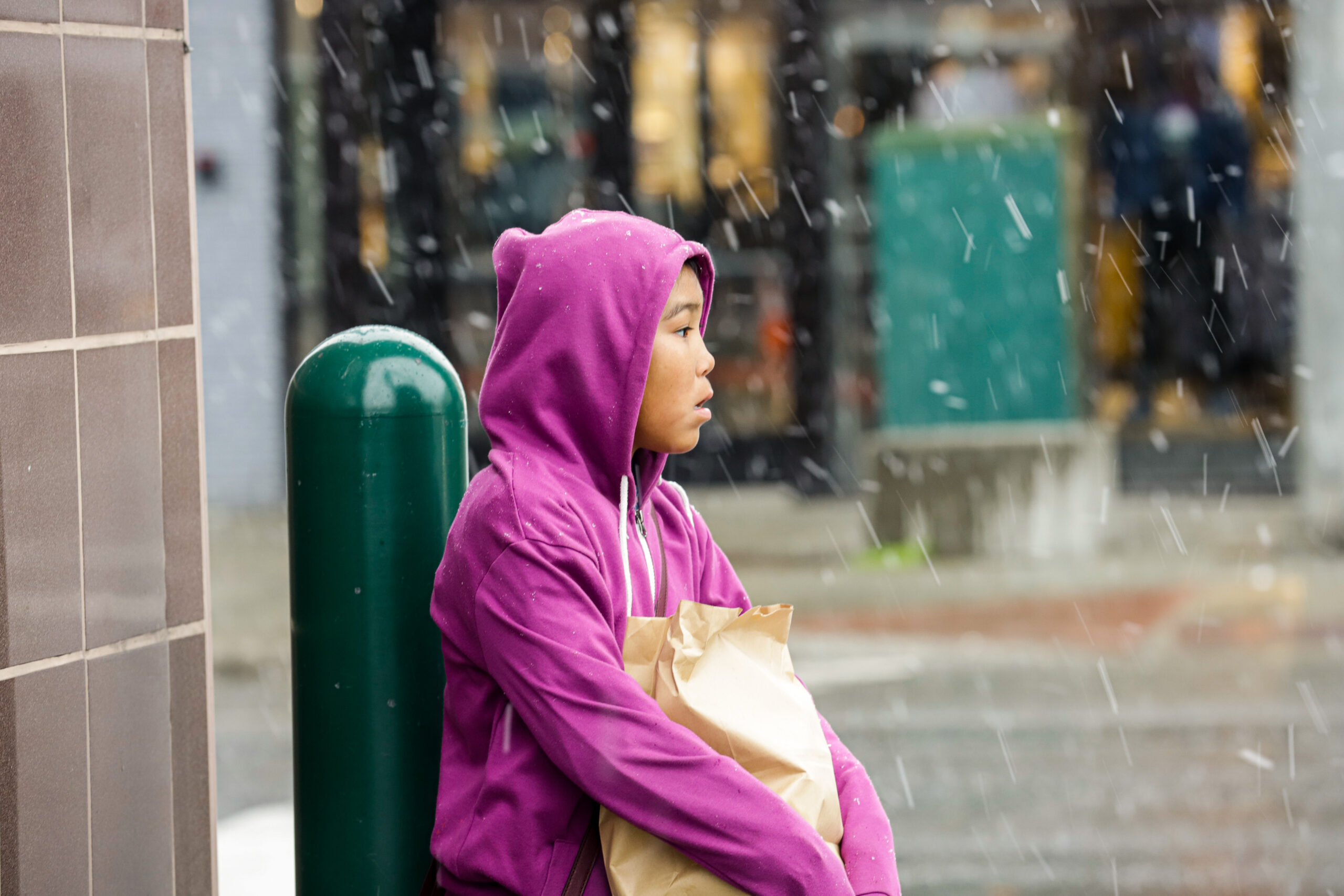A girl in a purple sweater stands outside in the snow.