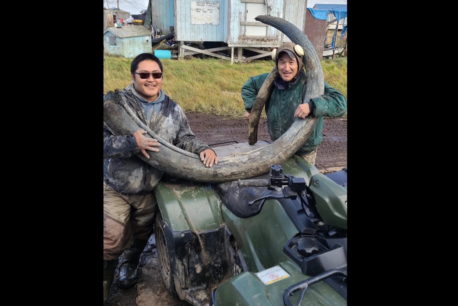 two men holding a mammoth tusk