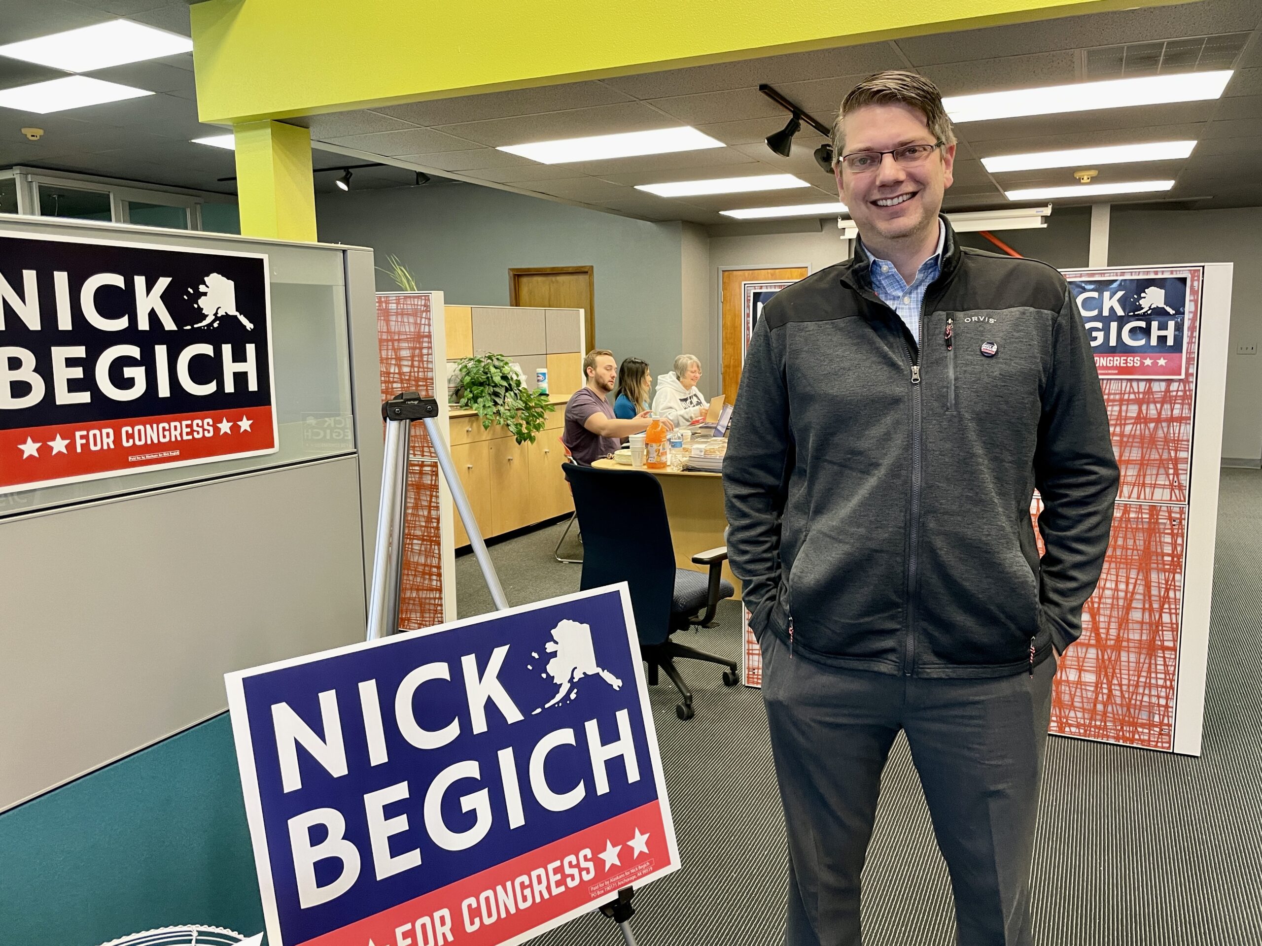 man in office with 'nick begich' signs