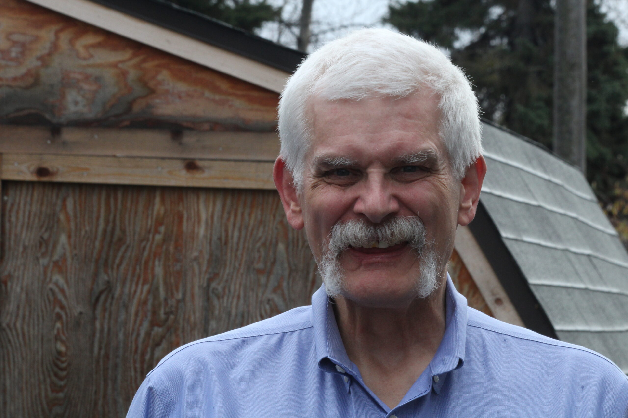 white-haired man with blue shirt smiles