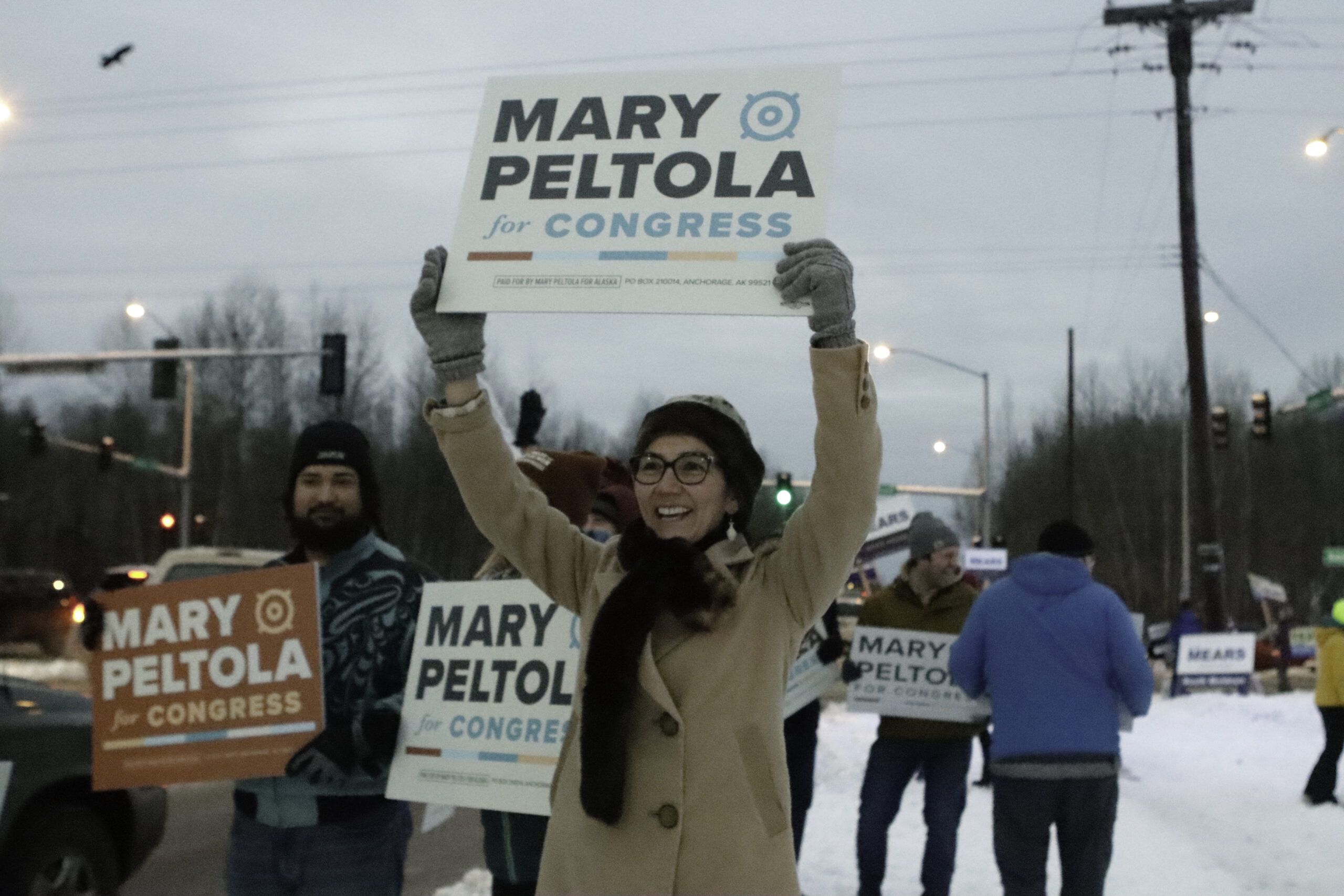 A woman holds a "Mary Peltola for Congress" sign outside
