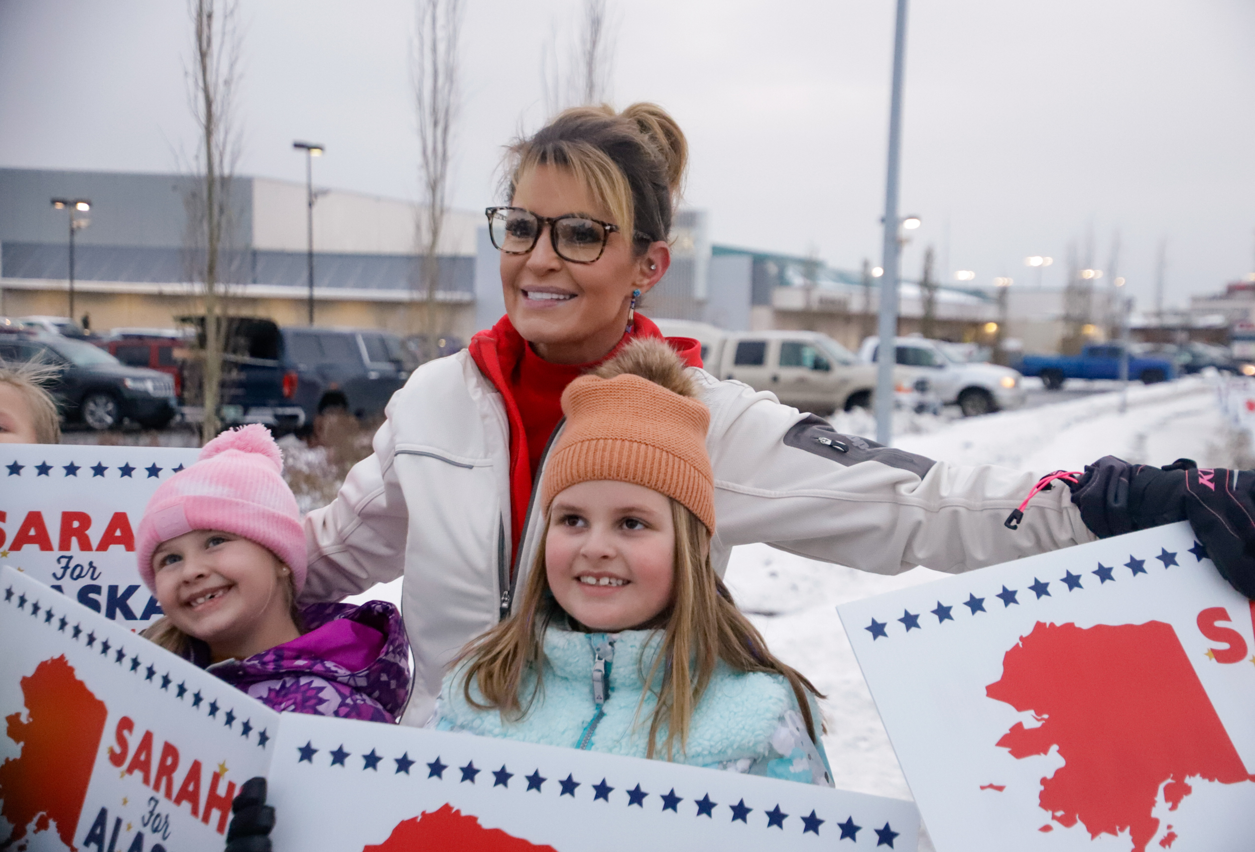 A woman and two children pose for a photo, holding Sarah for Alaska signs