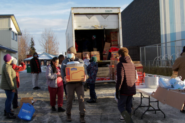People gather around a truck full of cardboard boxes.
