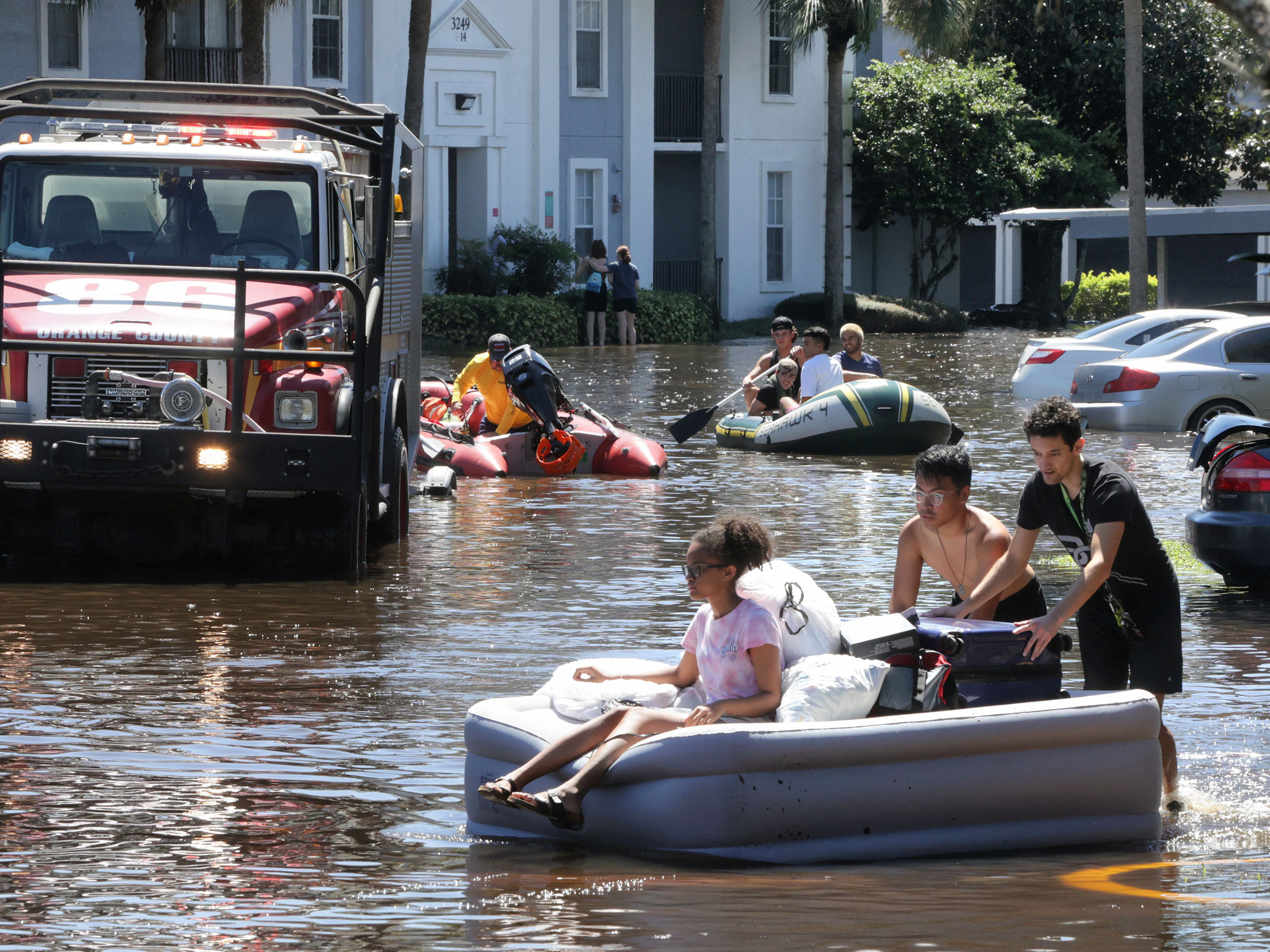 people on a inflatable bed on a flooded roadway