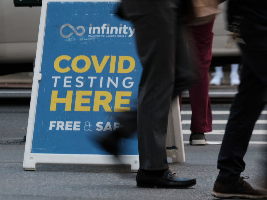 people walk by a COVID testing sign