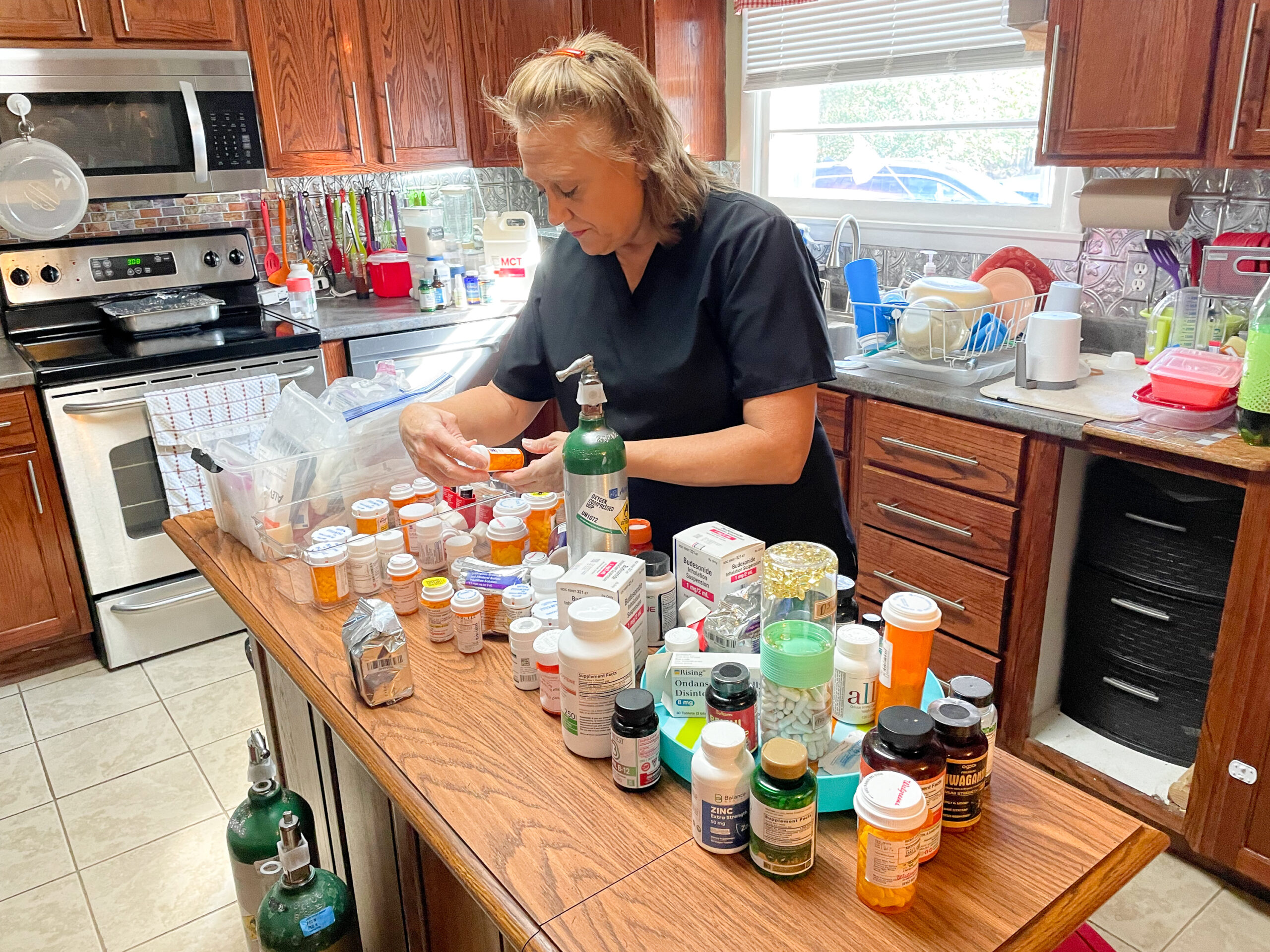 a woman stands at a table with a lot of pill bottles