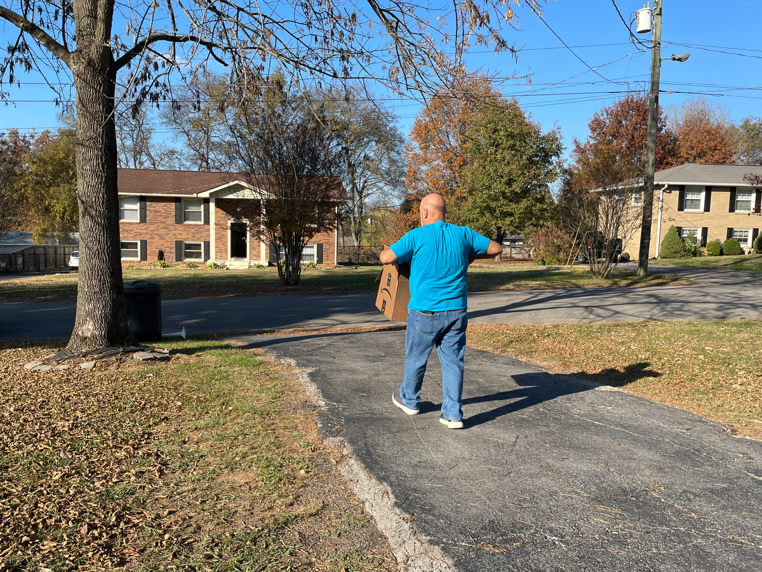 a man in a blue t-shirt carries a box to the curb