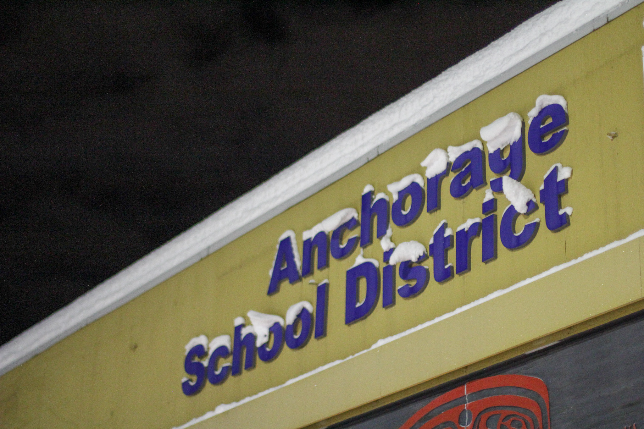 A sign displaying "Anchorage School District" with snow on the letters.