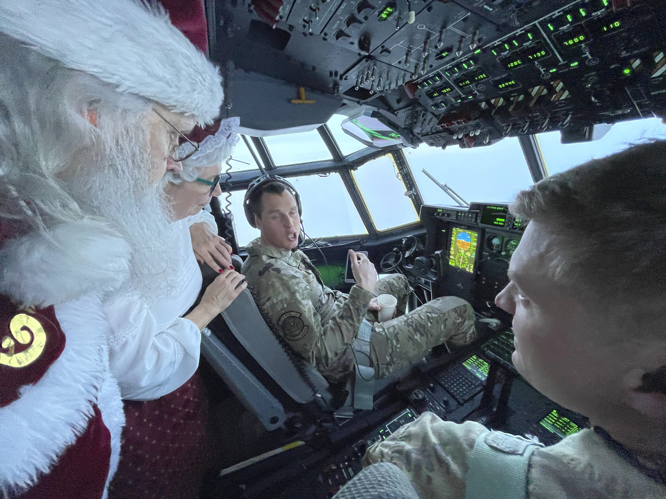 santa and mrs. claus talk to two people in the national guard, piloting a large plane