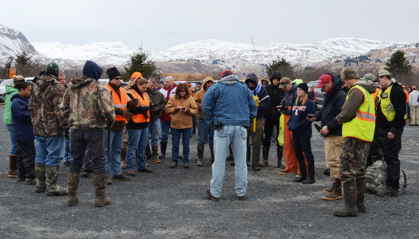 a group of people gather outside, in front of a snowy mountain