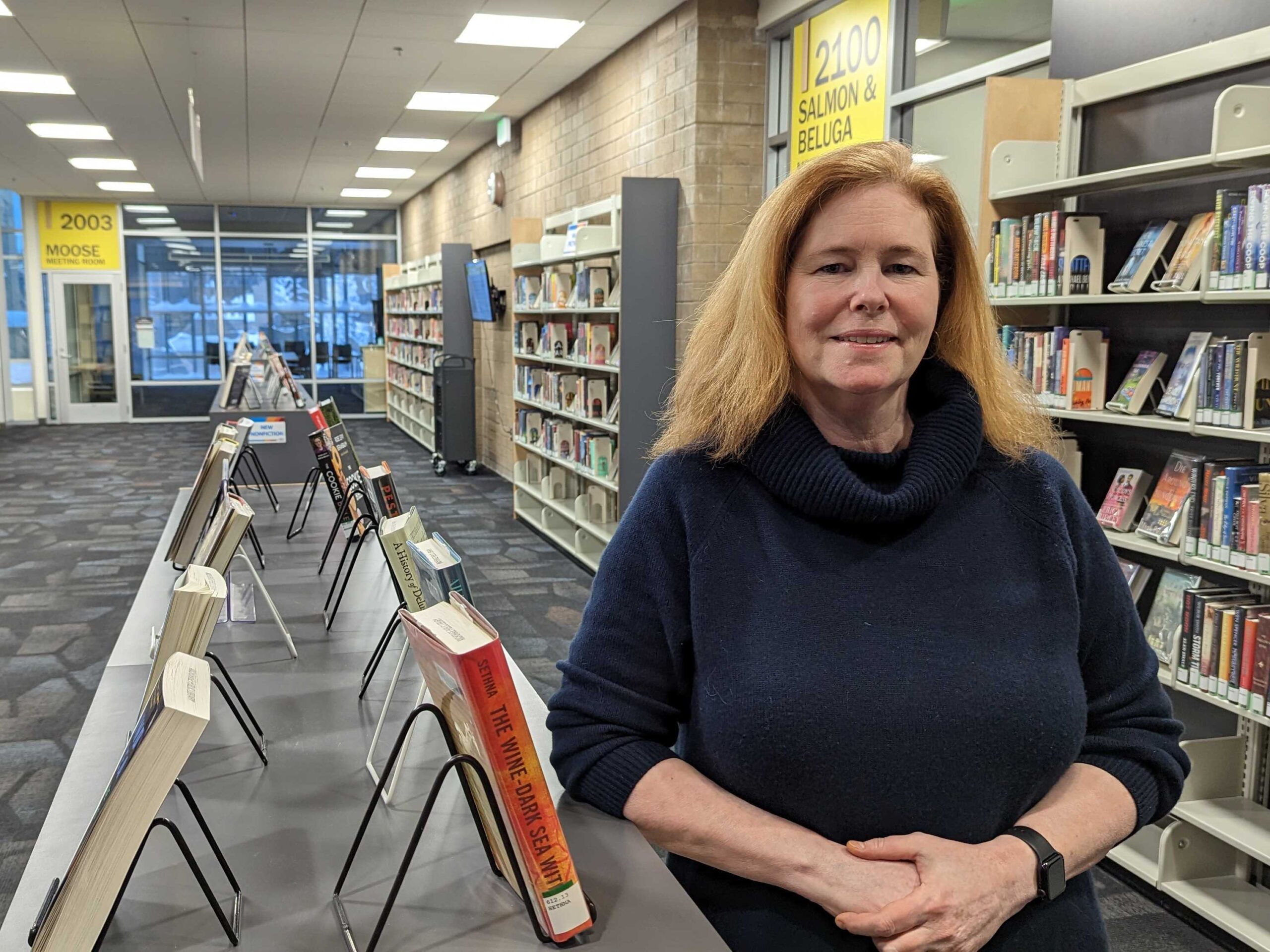 A woman poses in front of books