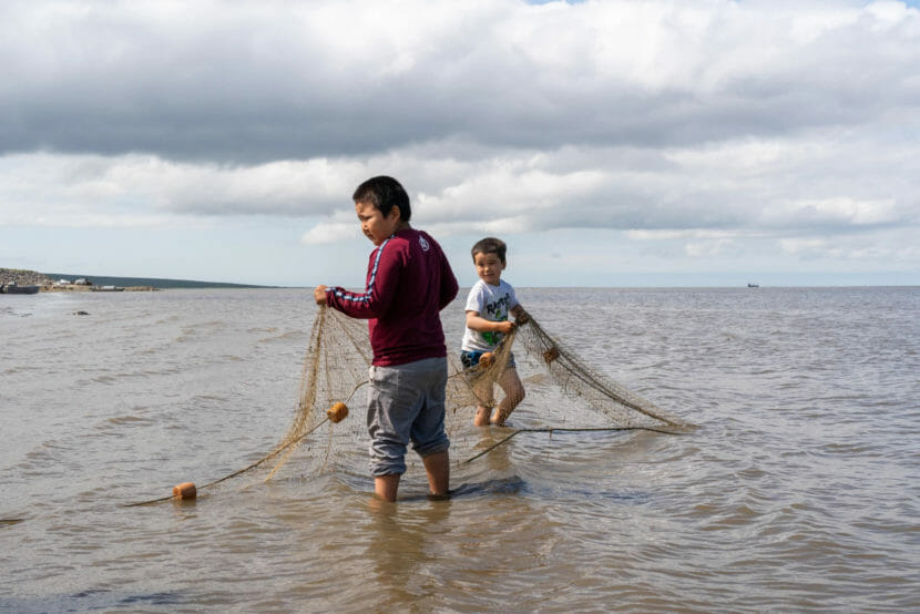 two children with a fishing net in the water