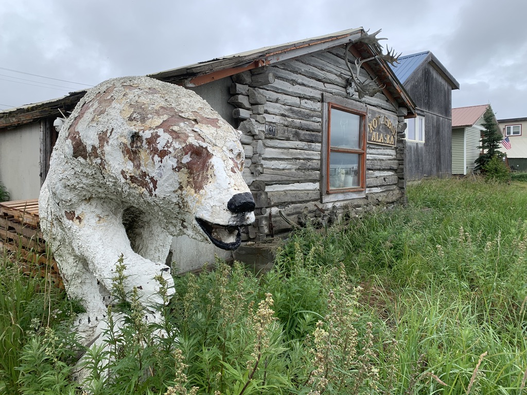 a worn polar bear statute near a wooden home