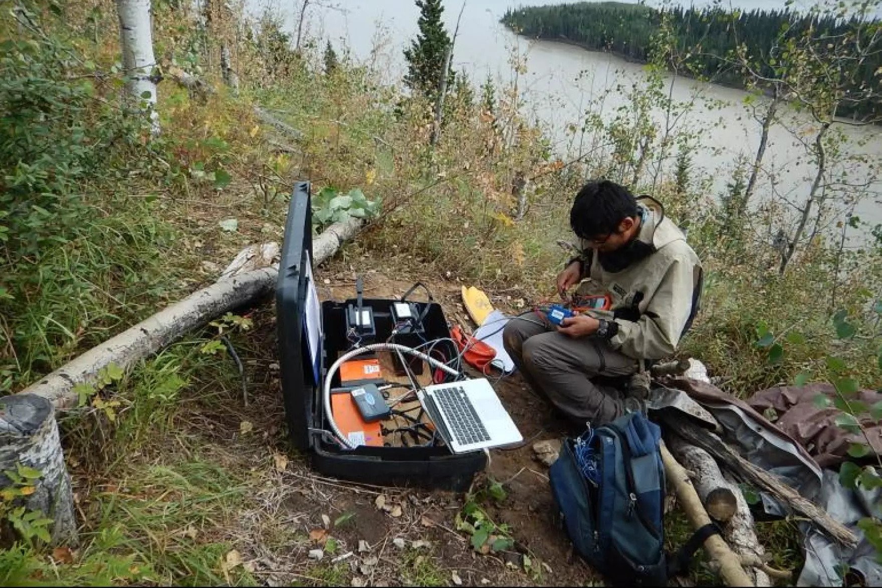 a person works at a computer outside, with other equipment