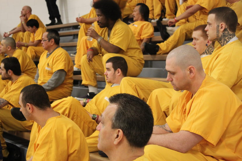 Prisoners in yellow jumpsuits on bleachers
