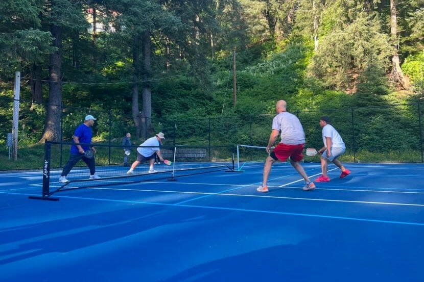 a group of people play pickleball outside