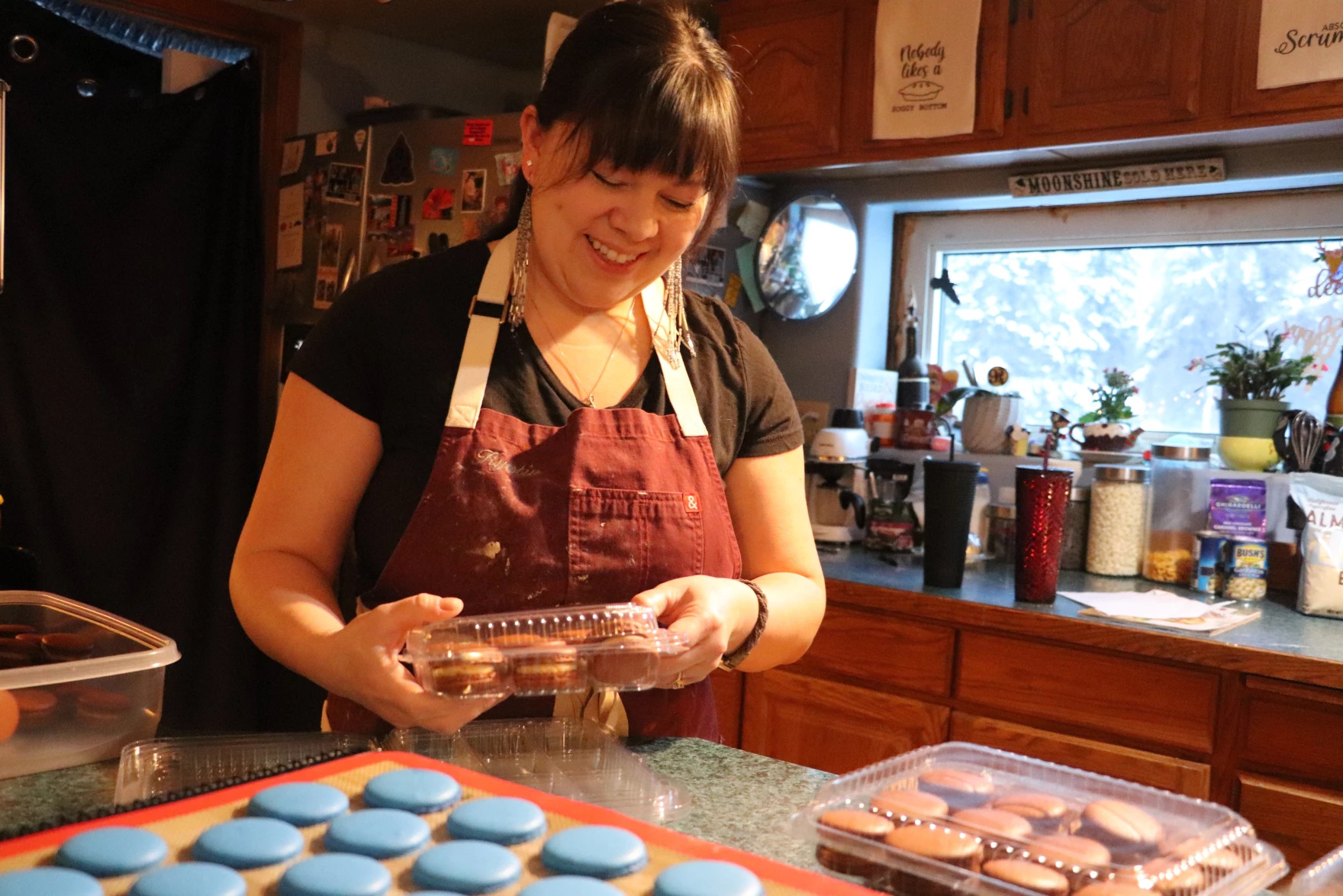 a woman putting macaroons in a plastic container