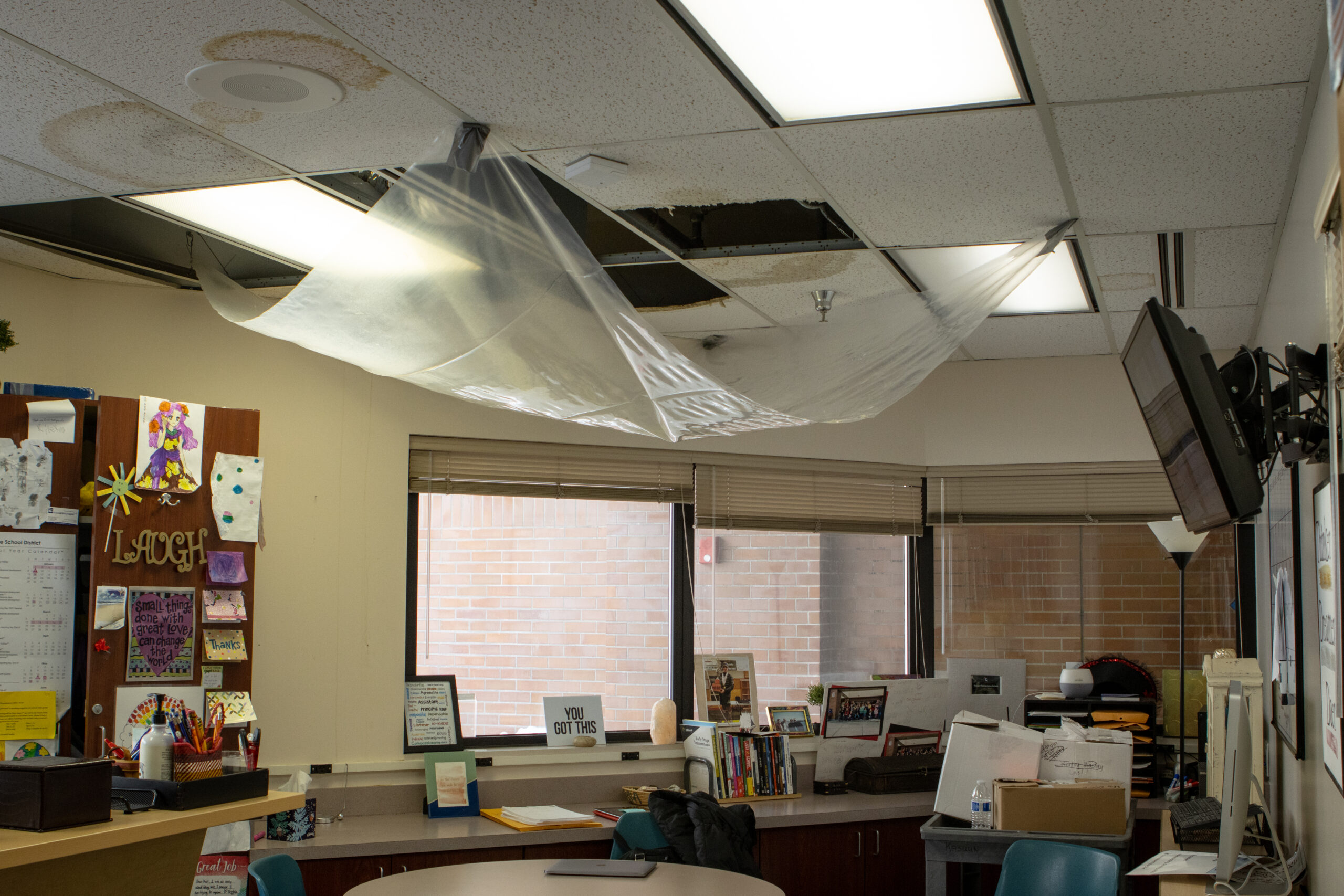 A schools office space with a damaged roof and ceiling