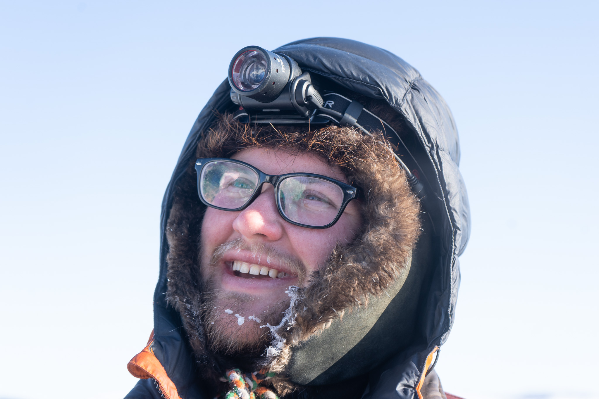 A white man with a small beard and with a headlamp and parka
