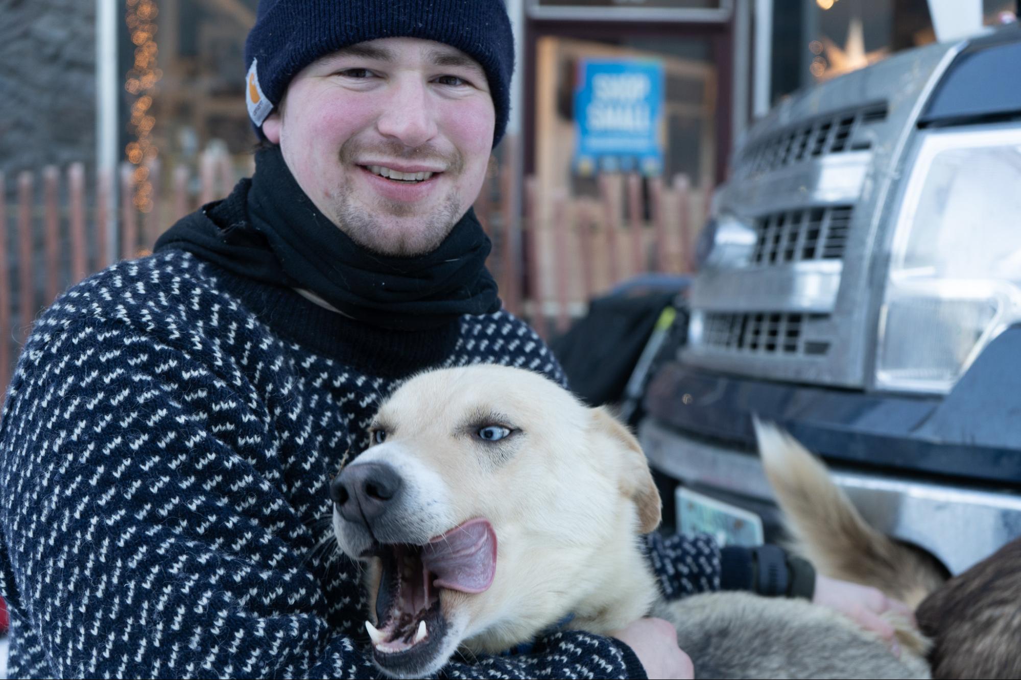 a man in a sweater with his arms around a dog