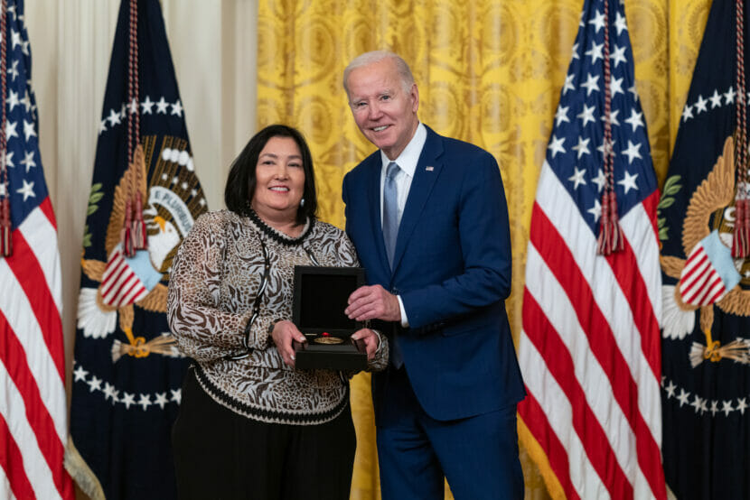 the presdident stands with a woman, holding an award