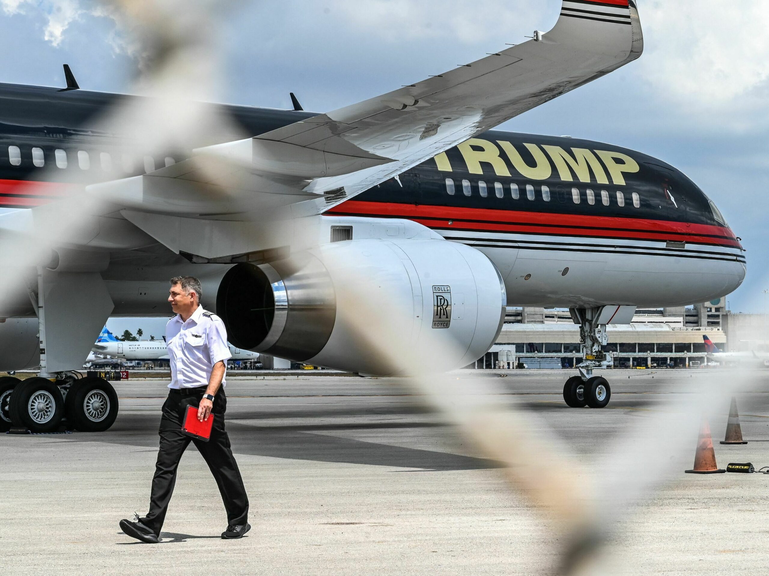 A pilot walks by a plane that says Trump on it