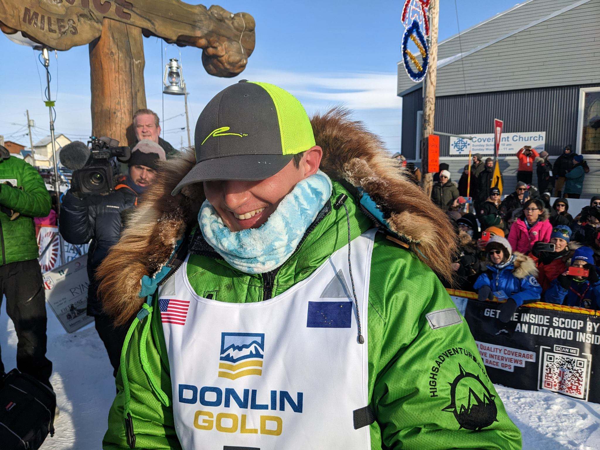 a musher in a green jacket