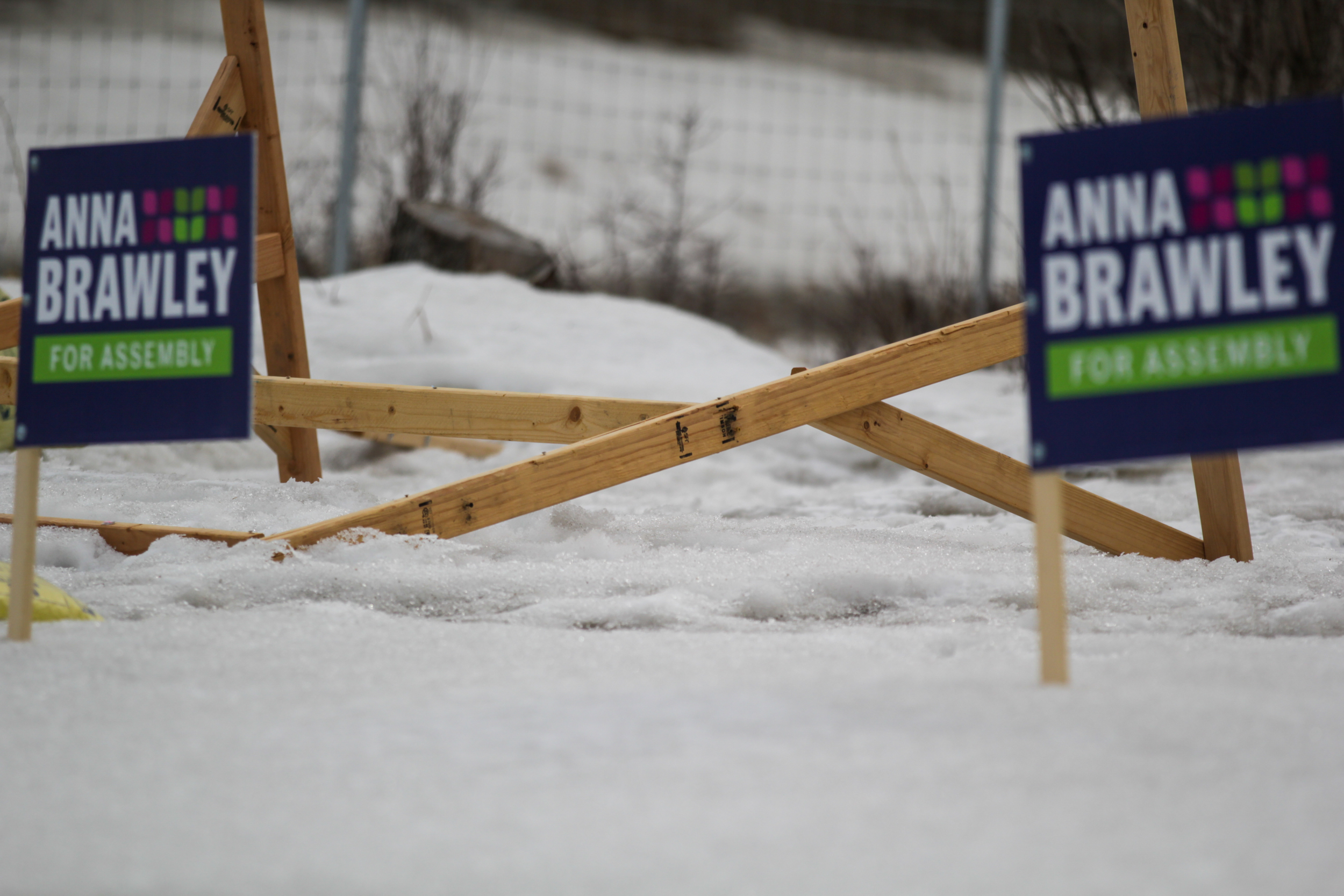 Two small political campaign signs frame a large, overturned campaign sign.