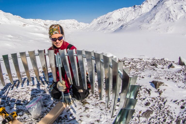 A scientist installs a weather station on a glacier in Alaskan mountains