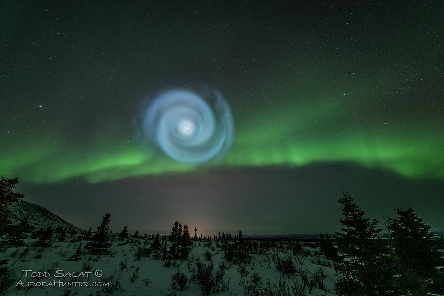 a spiral blue image in the sky with auroras in the background