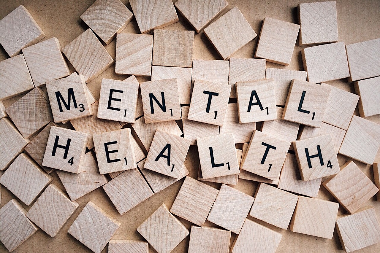 Scrabble pieces on wood table. Letters read "MENTAL HEALTH"