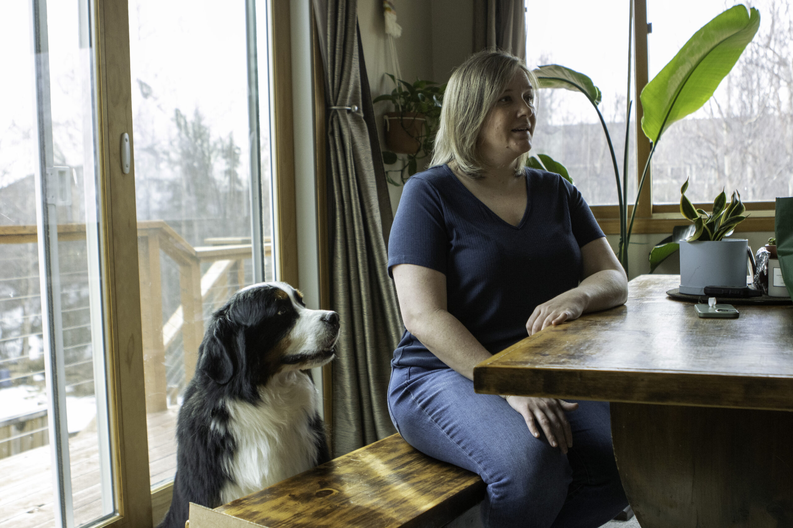 a pregnant mom sits at a table with a dog near