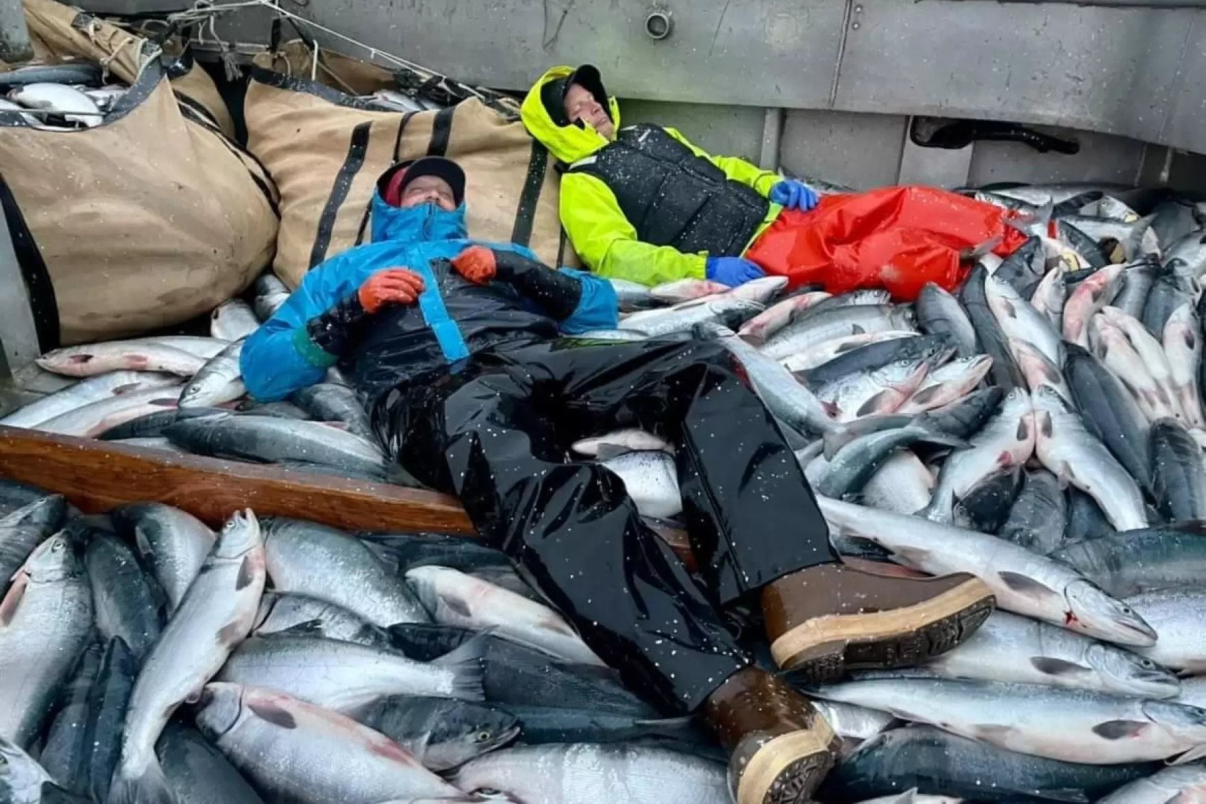 two people lay on a pile of fish