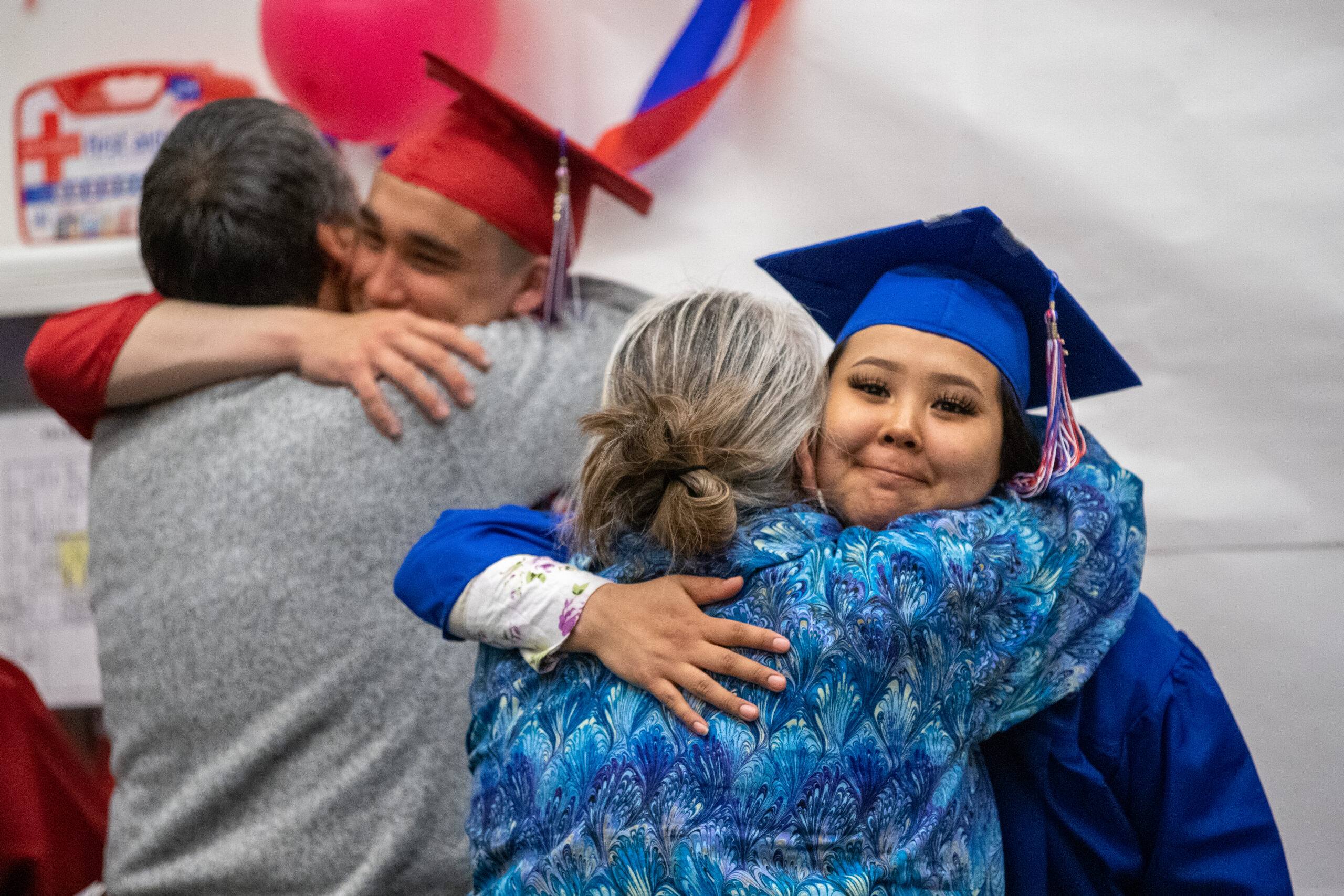 High school graduates hug friends and family after graduation.
