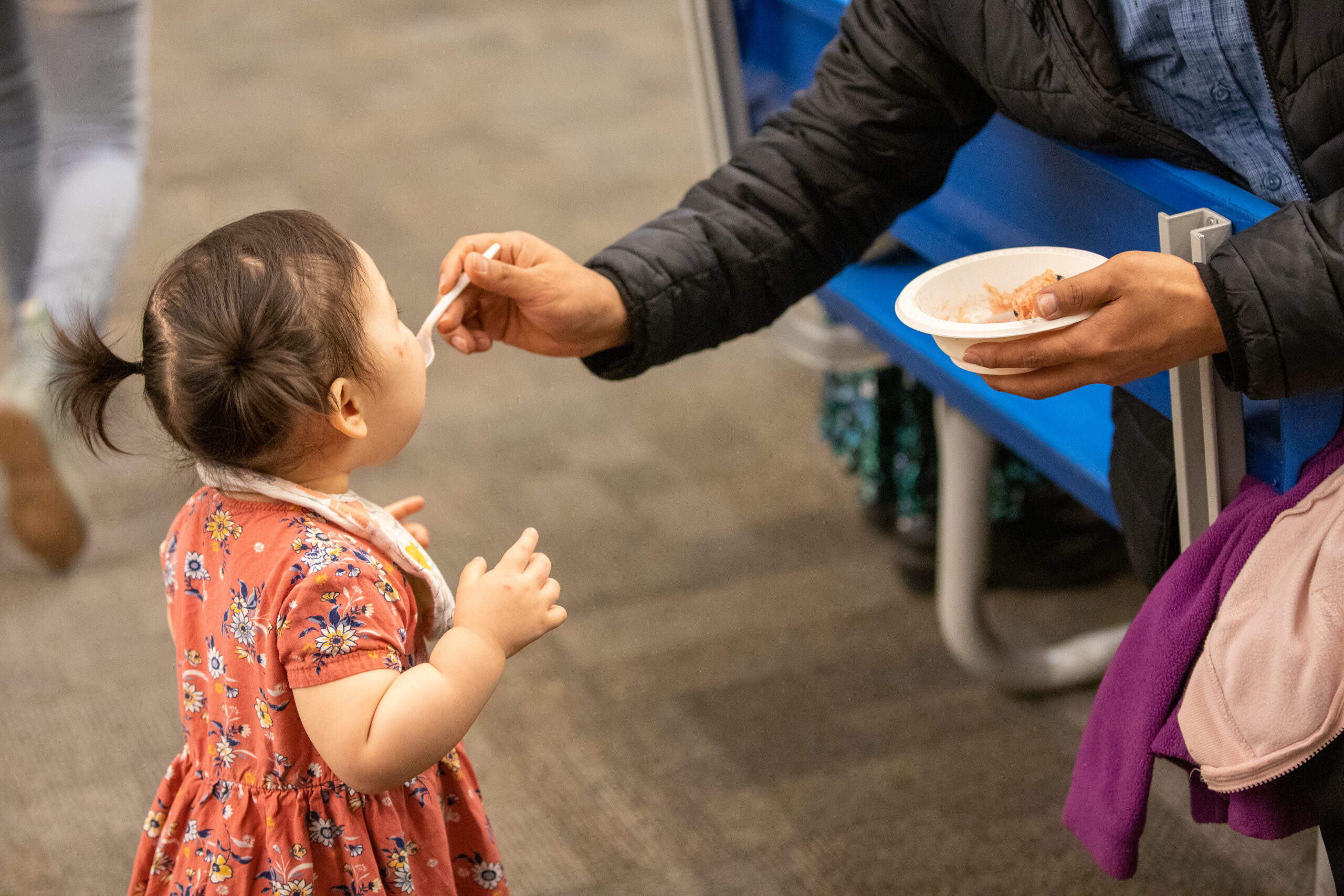 A man feeds his toddler daughter.