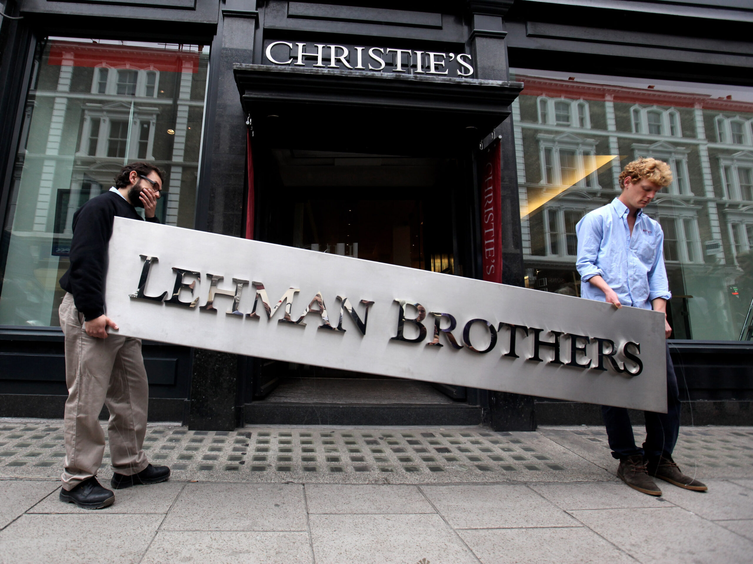 two people hold a sign that says "Lehman Brothers"