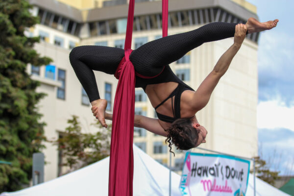 A woman performs acrobatics on an aerial silk display.