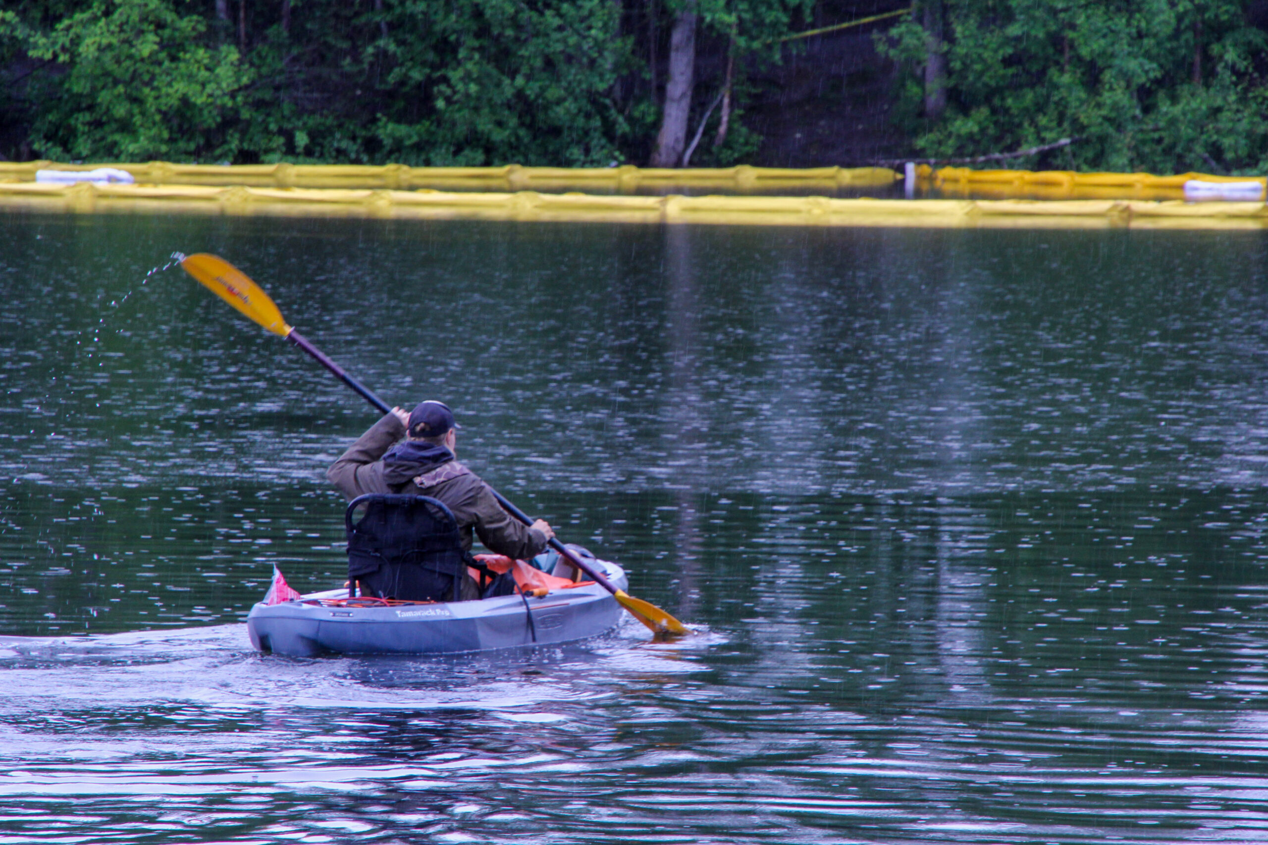 A man in a kayak near lines of yellow floats