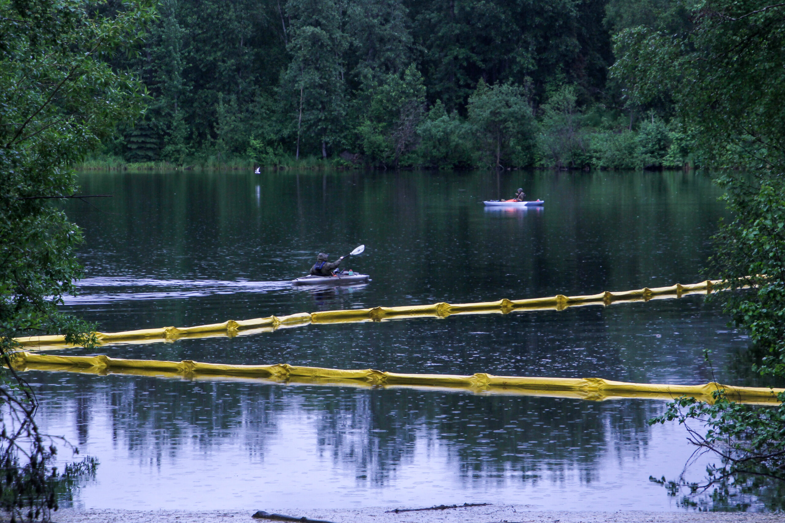 two kayakers in a lake next to lines of yellow floats