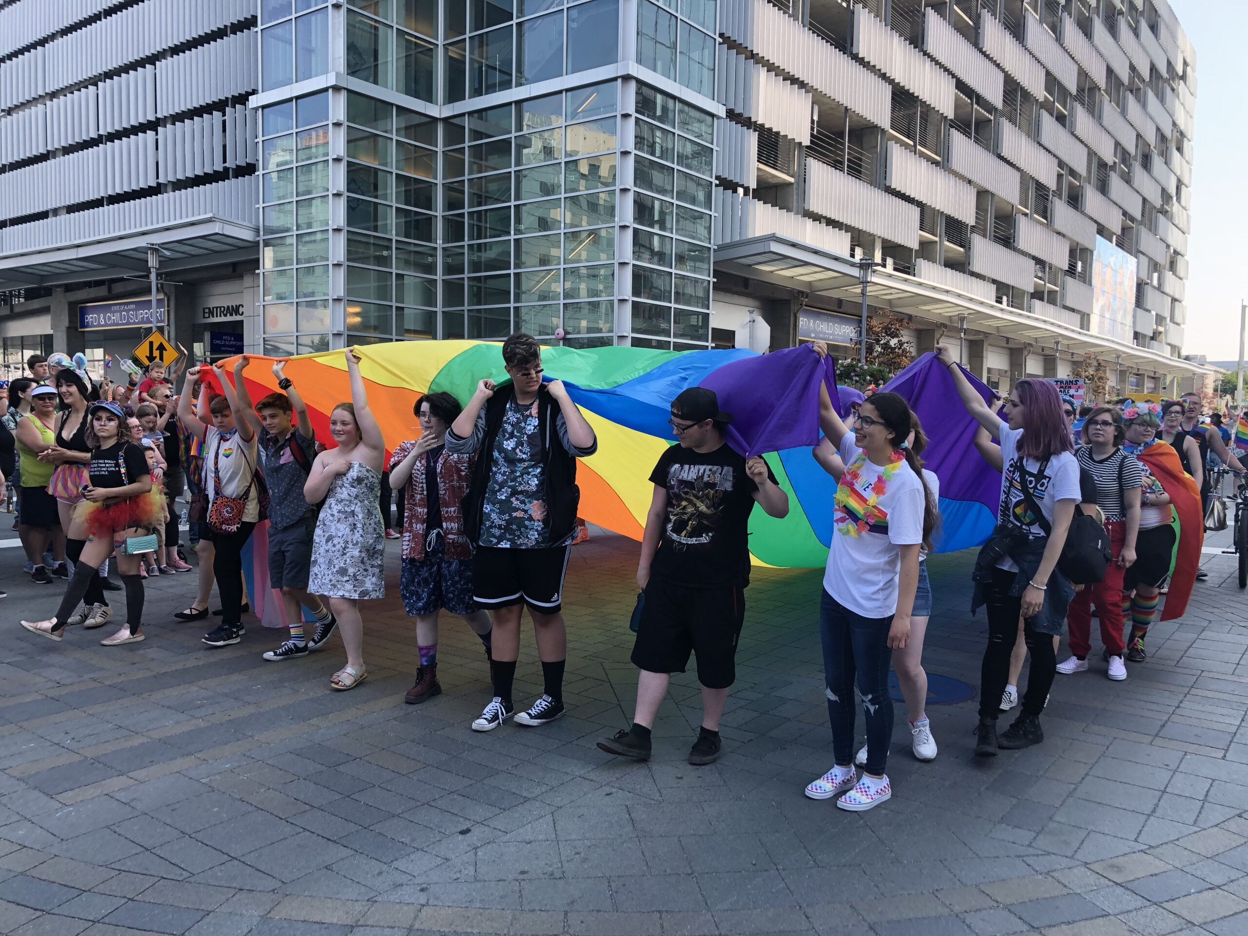 a group of people carry a giant rainbow flat