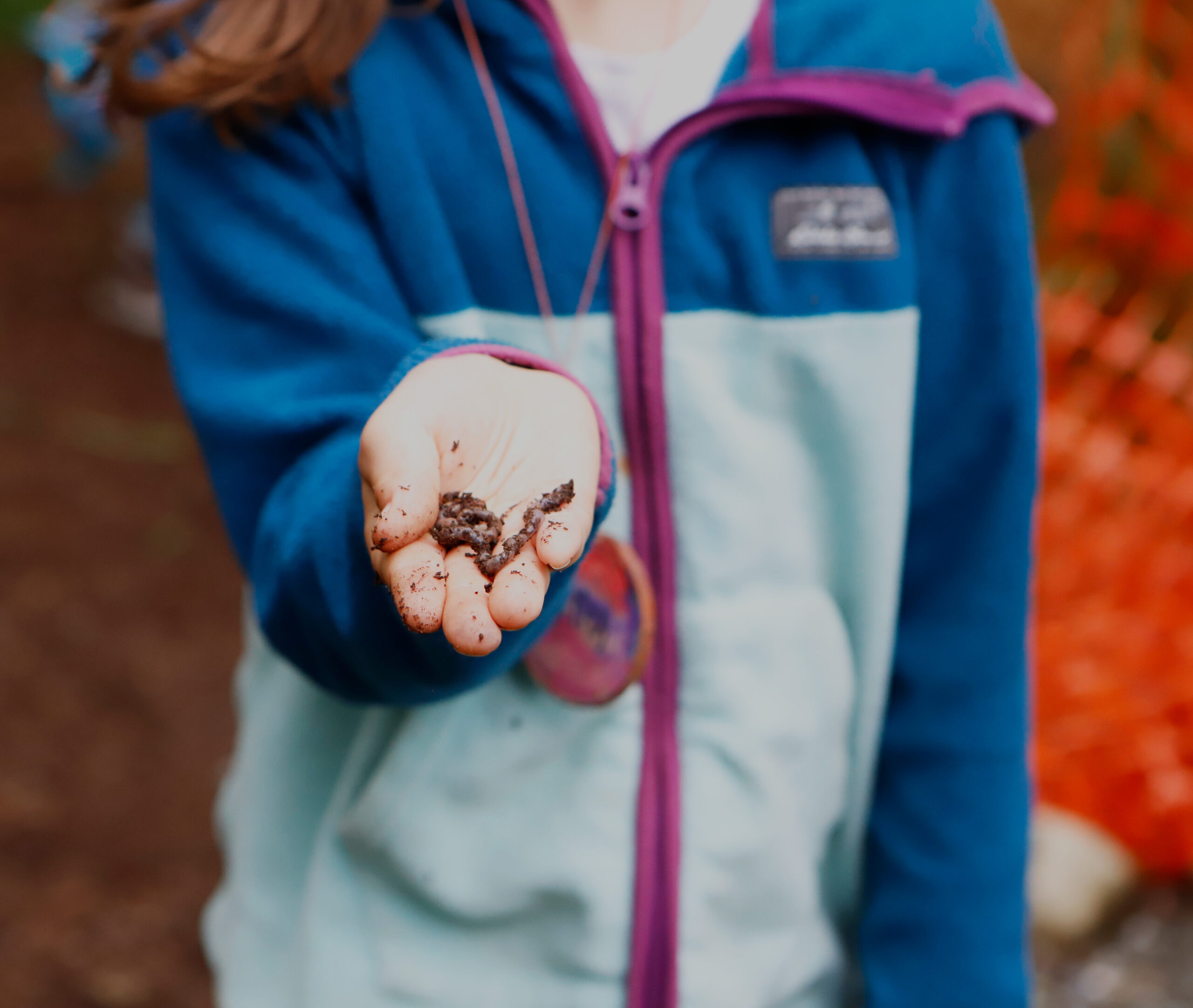 A girl holds a worm in her hand