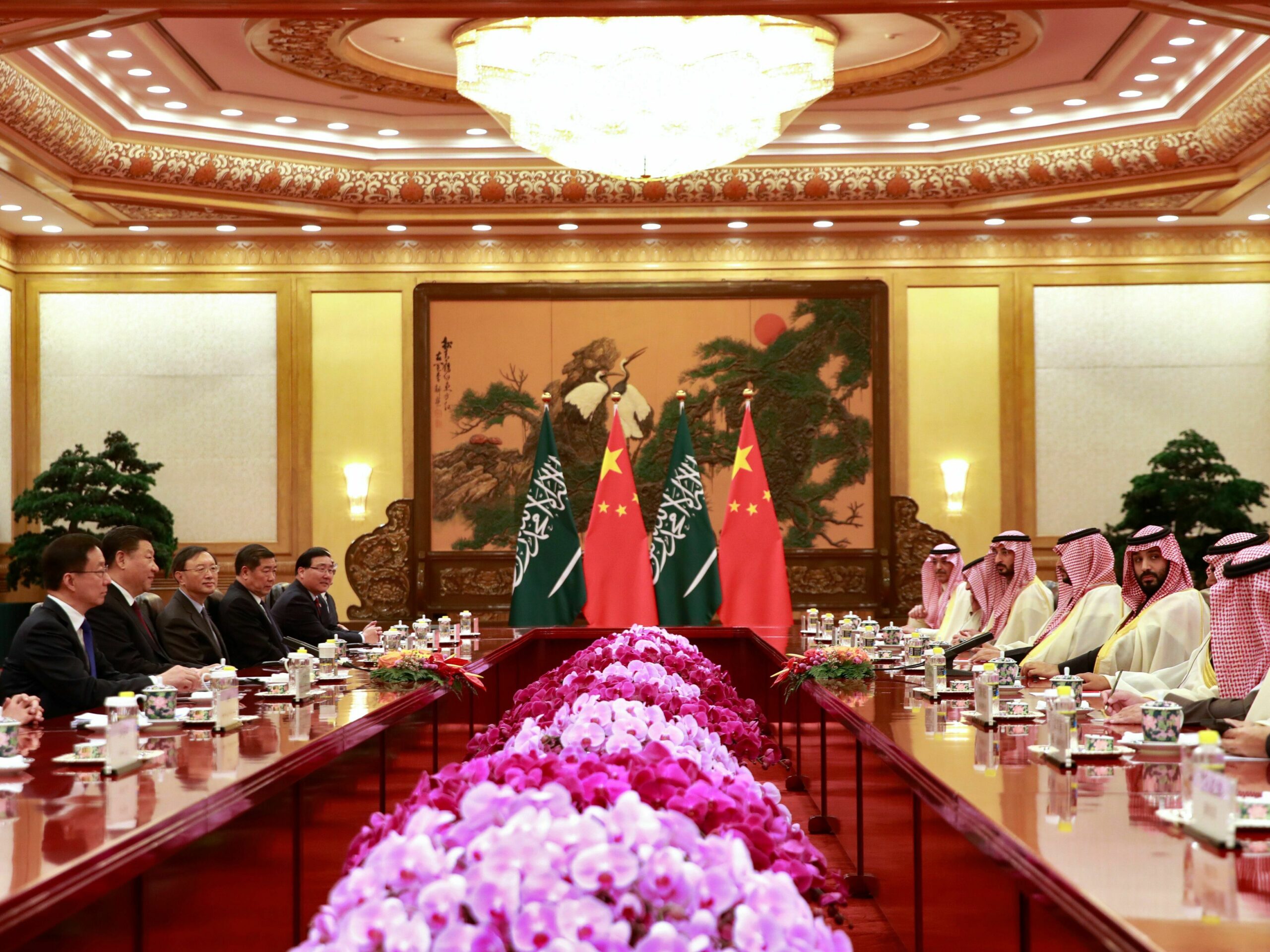 people in a meeting room with flowers on the table and China's flag displayed