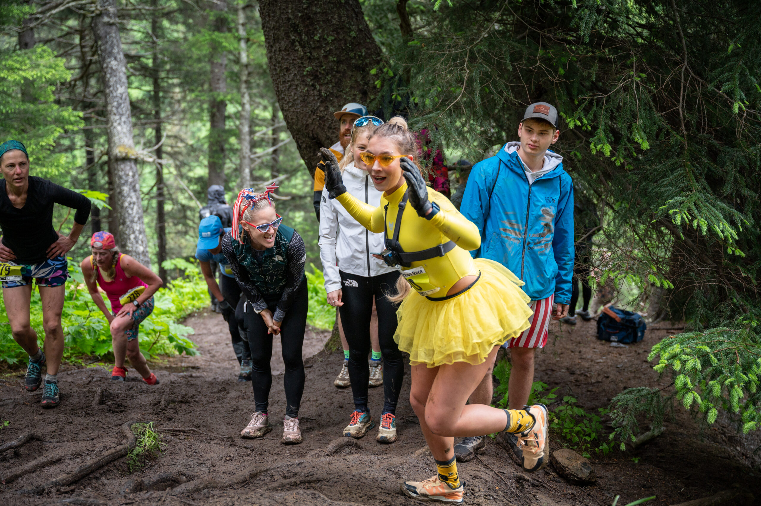 A woman in a yellow costume hikes a trail.