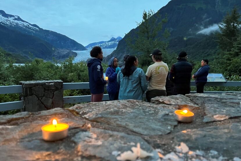 people stand together outside, near candles