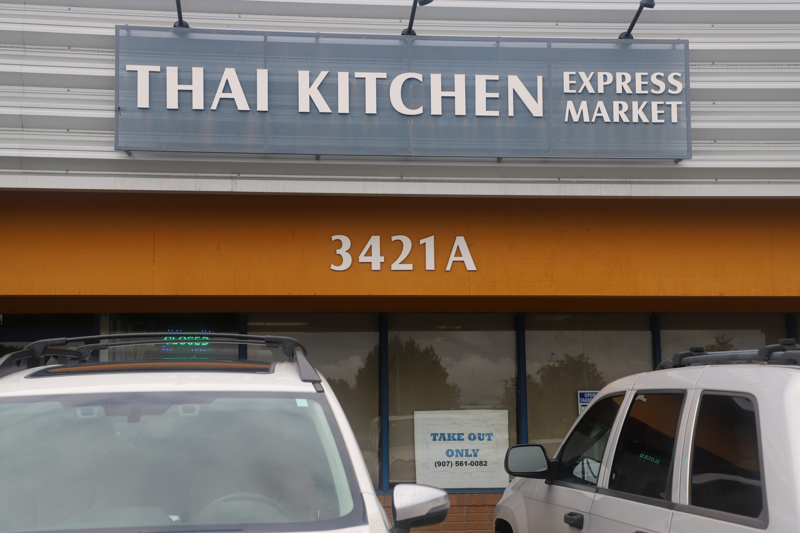 The exterior of a strip mall. A sign says "THAI KITCHEN EXPRESS MARKET."