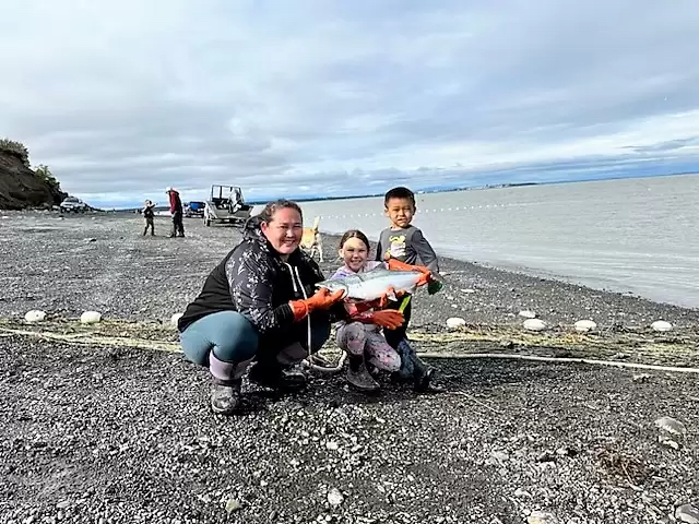 a woman and two children pose with a salmon