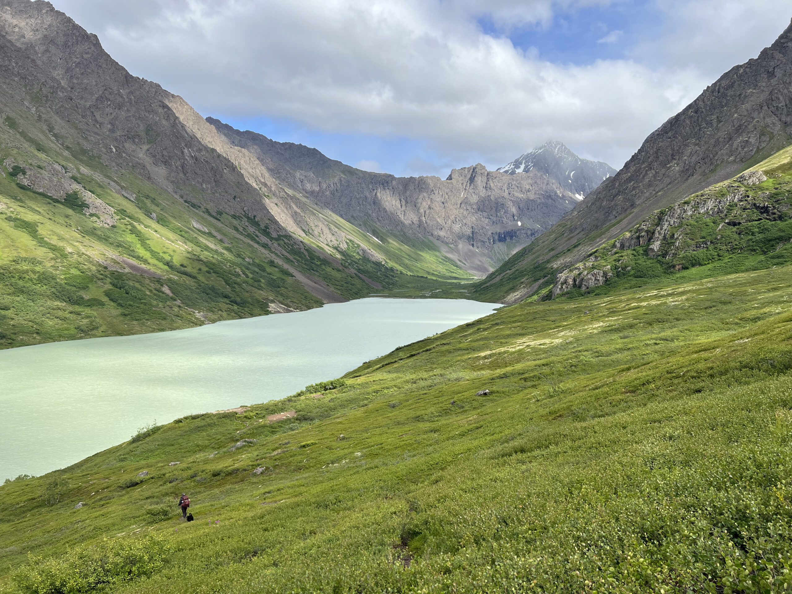 Landscape photo showing a brown lake in a mountainous valley.